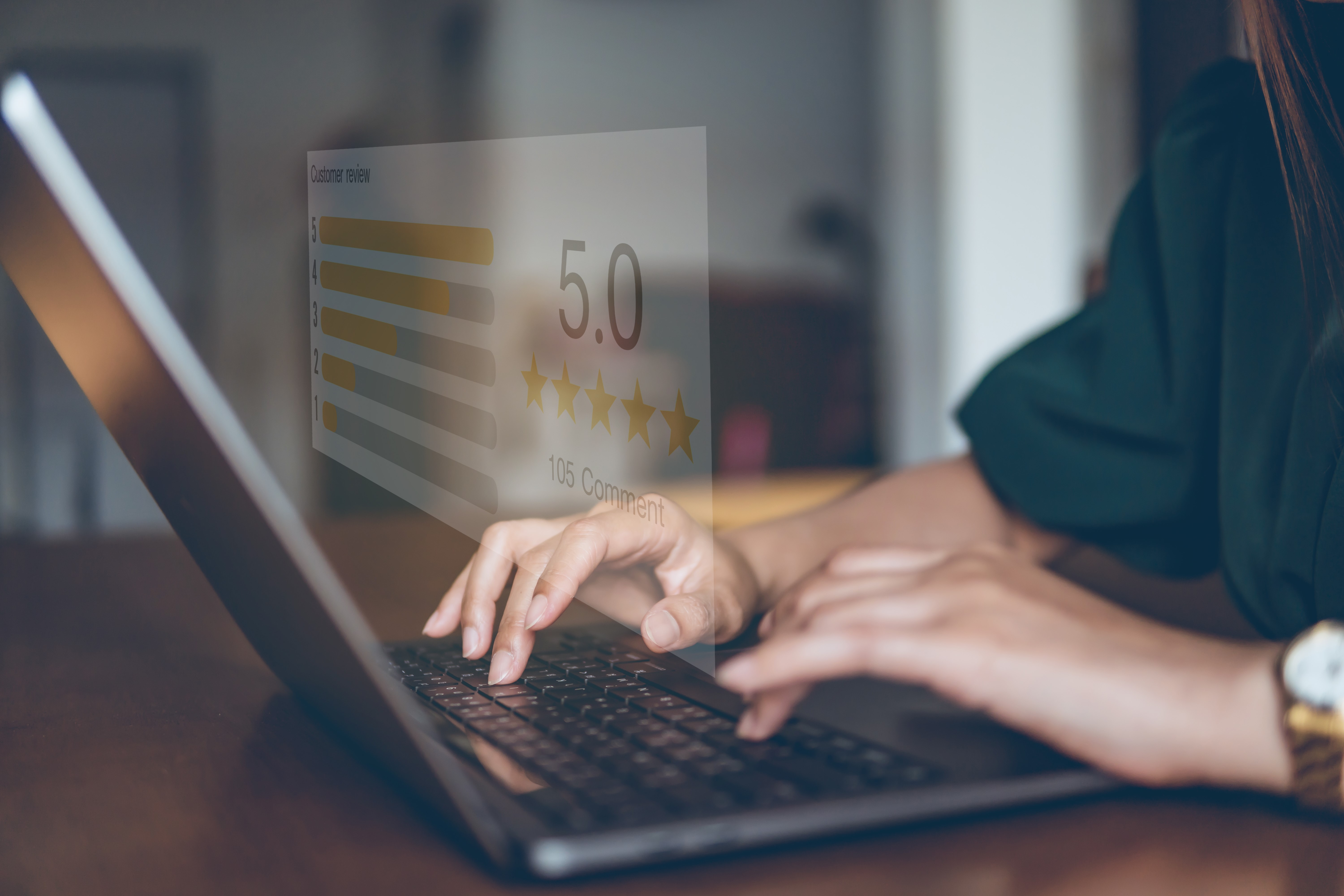 Hand at a laptop. Projected from the screen is a 5 star rating.