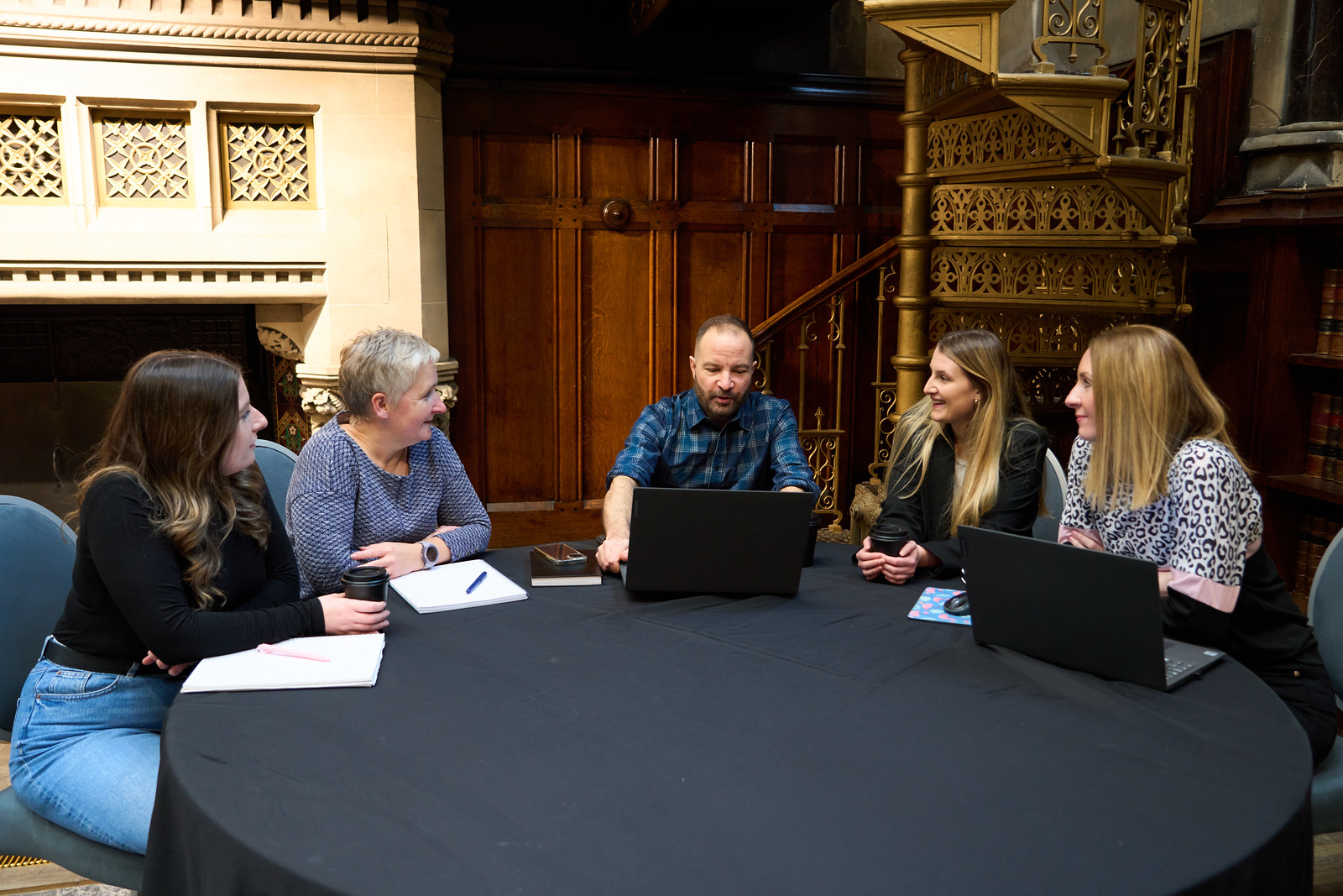 Team in conversation sitting at a black round table.