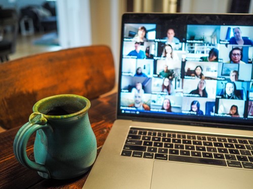 Laptop showing a zoom meeting. Next to it is a mug.