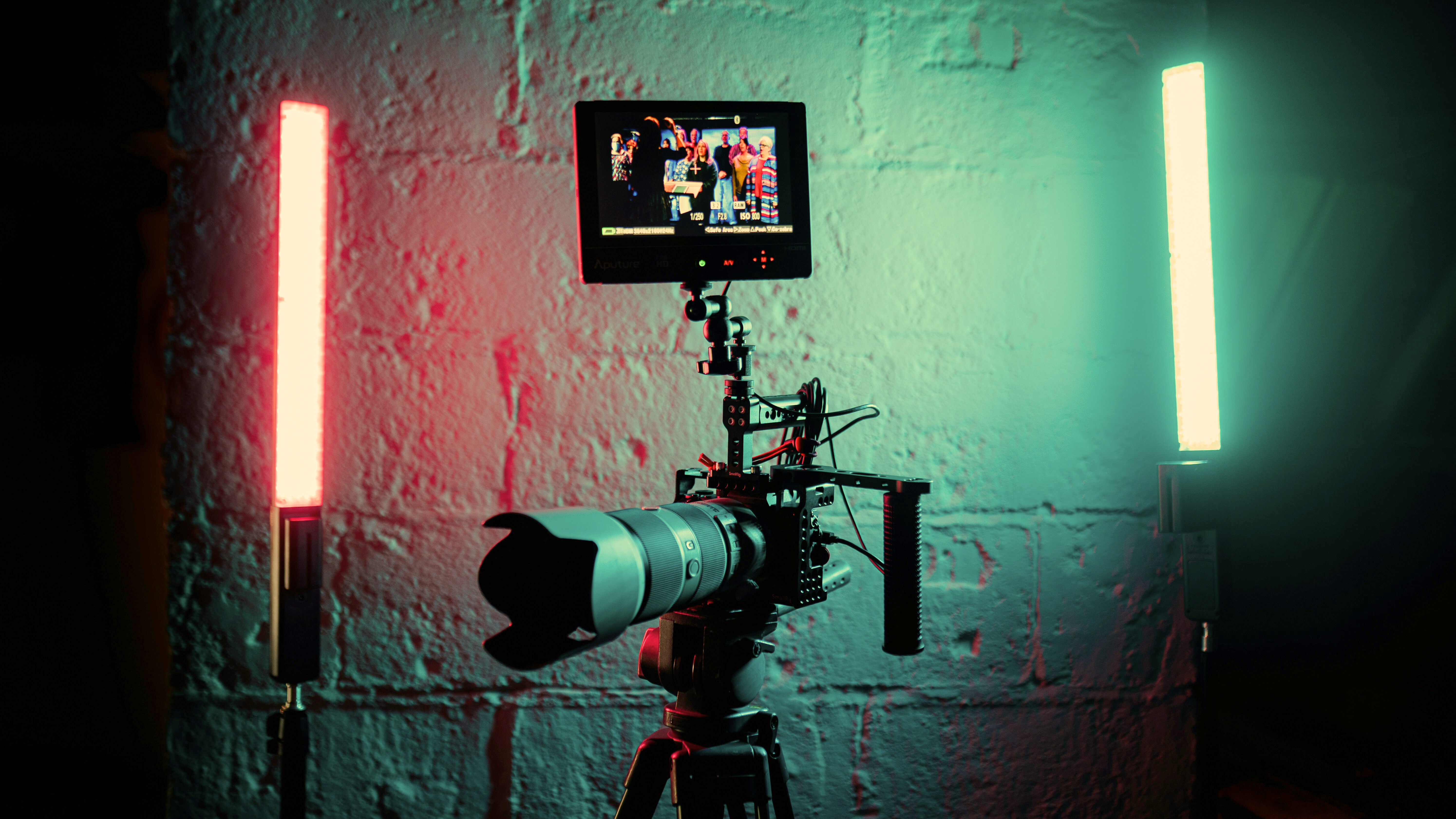 Film camera with fluorescent pink and green lights behind.