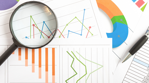 Magnifying glass on top of charts.