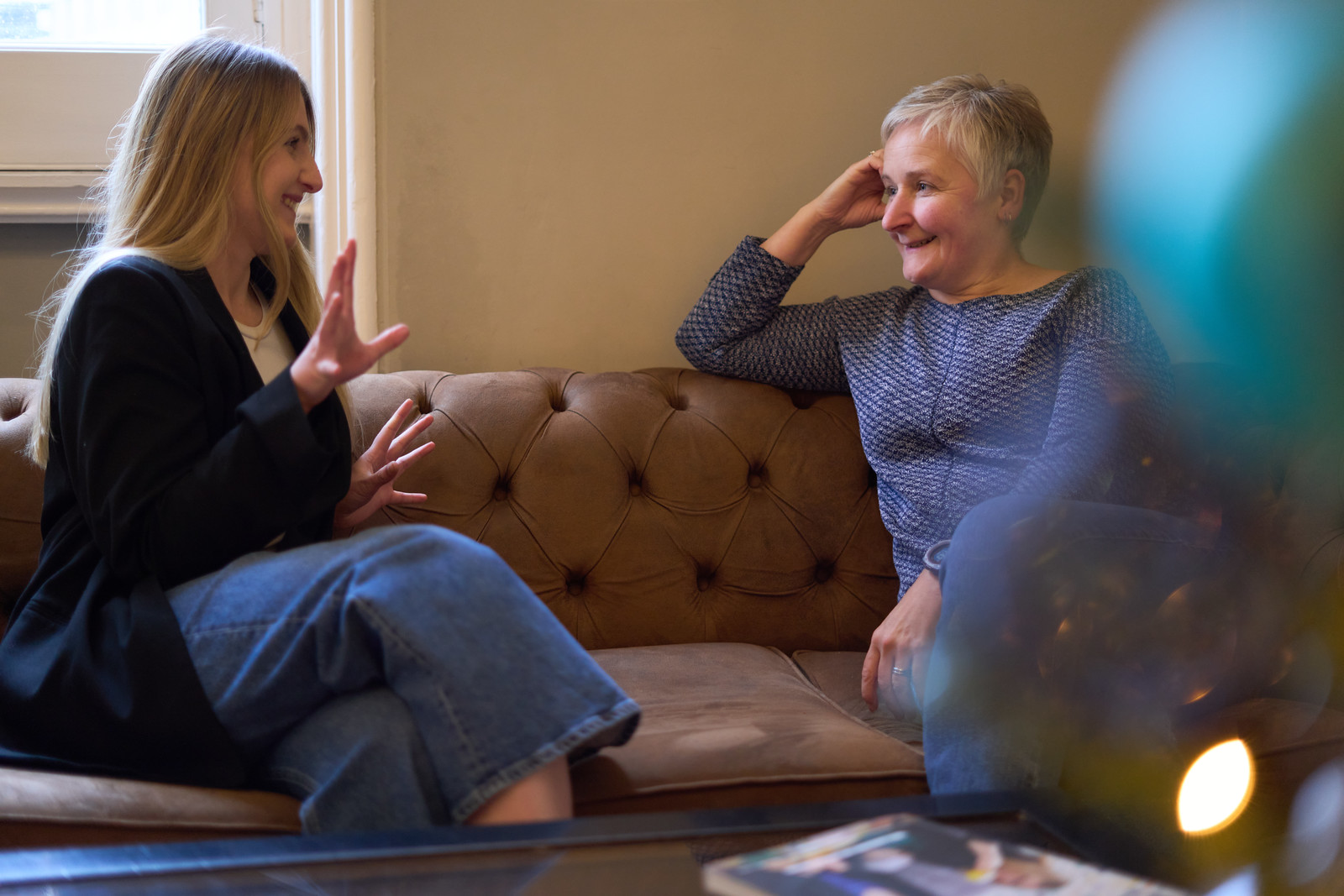 Erin and Alison talking and sitting on a sofa.