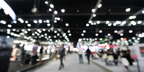 Image blurred out. In the background is an exhibition with lights and people.