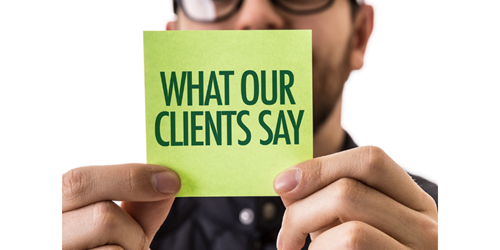 Man holding a post it note. On the post it note the words ' what our clients say'